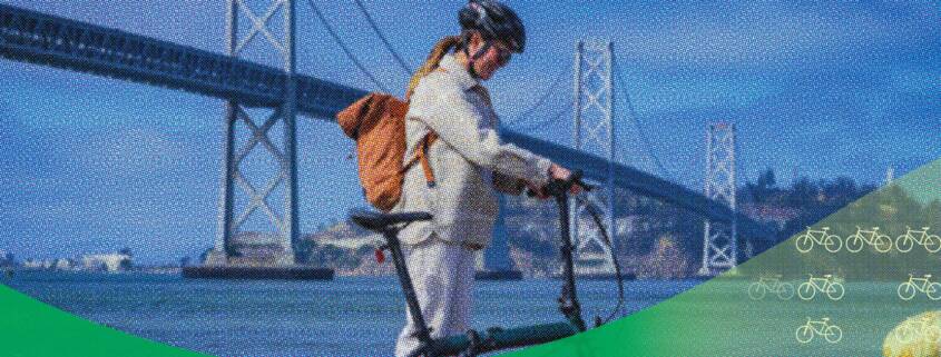 A cyclist with a backpack walks alongside an e-bike on San Francisco’s waterfront, with the Bay Bridge in the background, overlaid with blue halftone texture and green graphic waves.