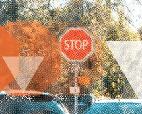 Orange stop signs give way to white yield triangles over a street scene dotted with bicycle icons, illustrating the Bicycle Safety Stop. A sign of progress.